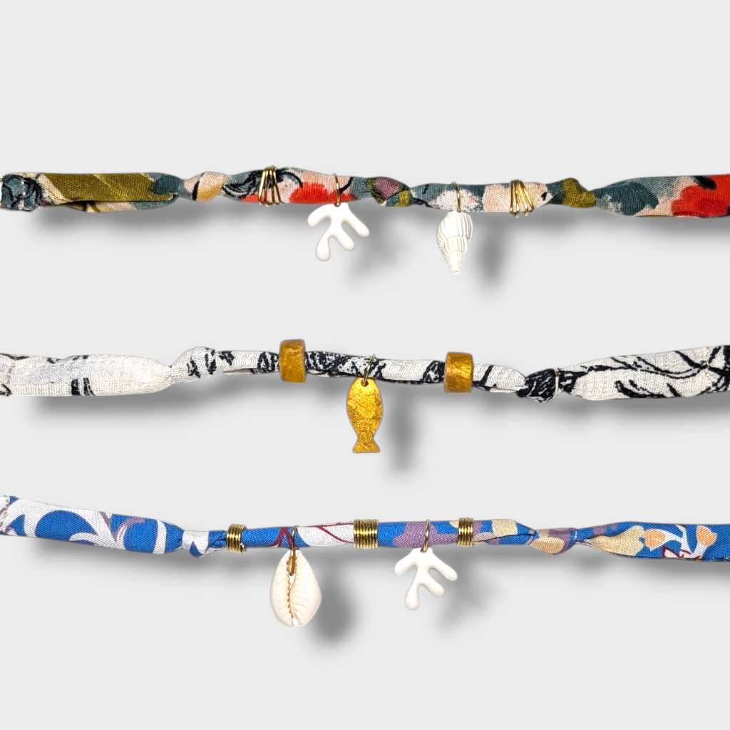 Alt text:
Χειροποίητα βραχιόλια από εμπριμέ υφασμάτινο κορδόνι με κοχύλια, κοράλλια και χρυσές λεπτομέρειες σε καλοκαιρινό ύφος.